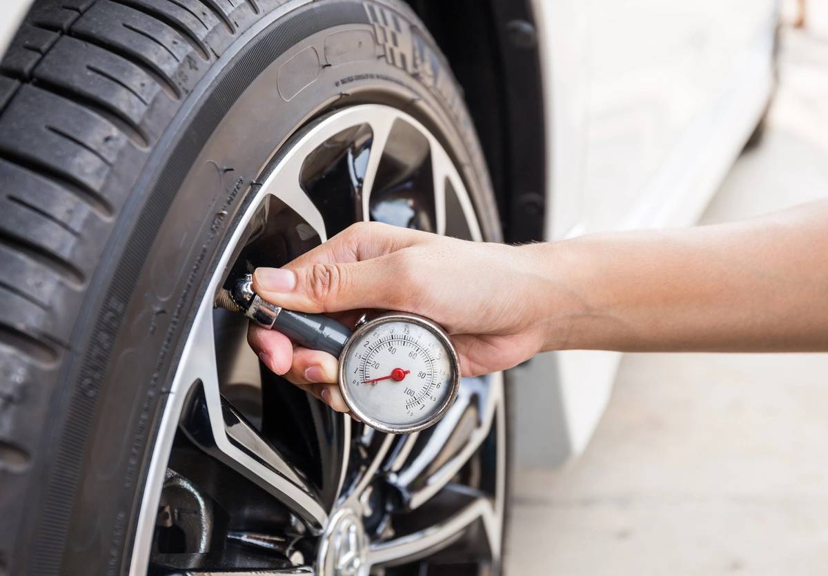 Close-Up Of Hand holding pressure gauge for car tyre pressure measurement
